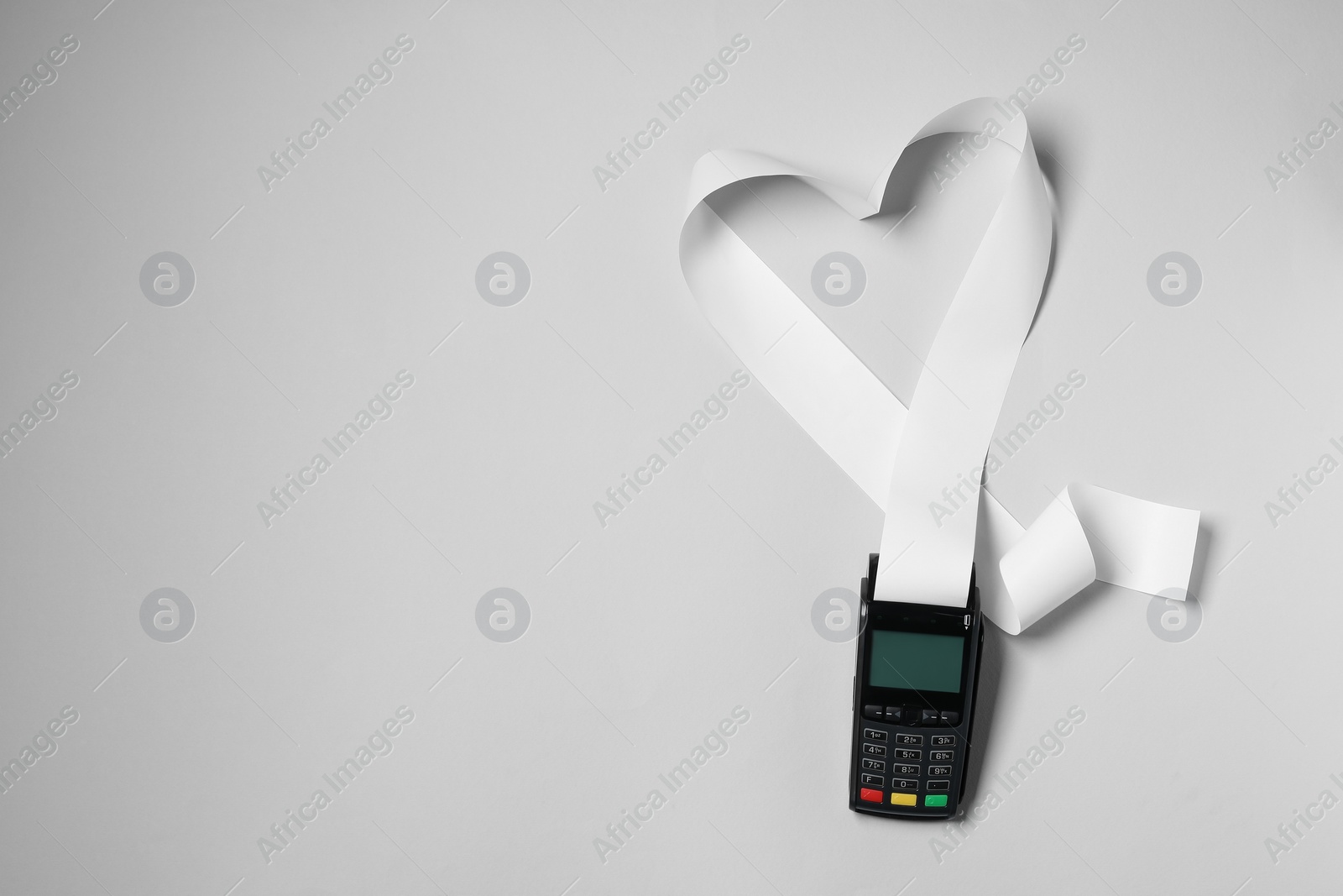 Photo of Payment terminal and heart made of thermal paper for receipt on light grey background, top view. Space for text