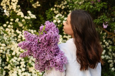 Photo of Woman with lilac flowers outdoors, back view