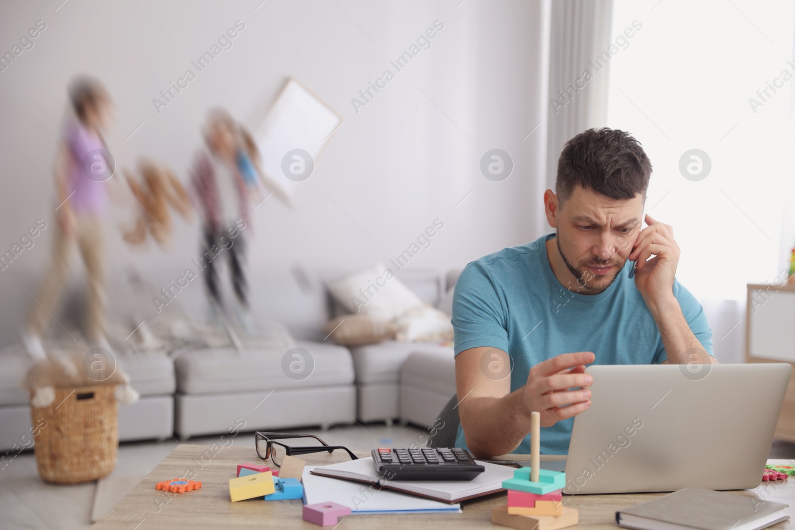 Image of Children disturbing overwhelmed man in living room. Working from home during quarantine