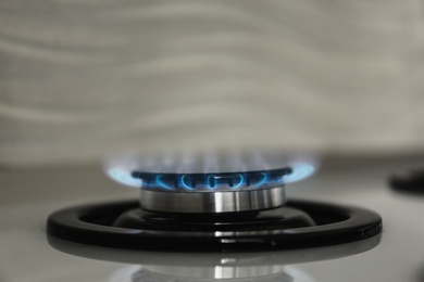 Photo of Gas burner with blue flame on modern stove, closeup. Space for text