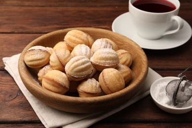 Delicious nut shaped cookies with boiled condensed milk and powdered sugar on wooden table
