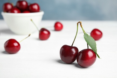 Ripe sweet cherries on white wooden table. Space for text