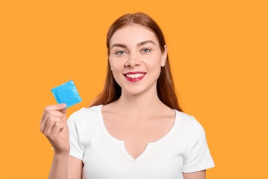 Woman holding condom on yellow background. Safe sex