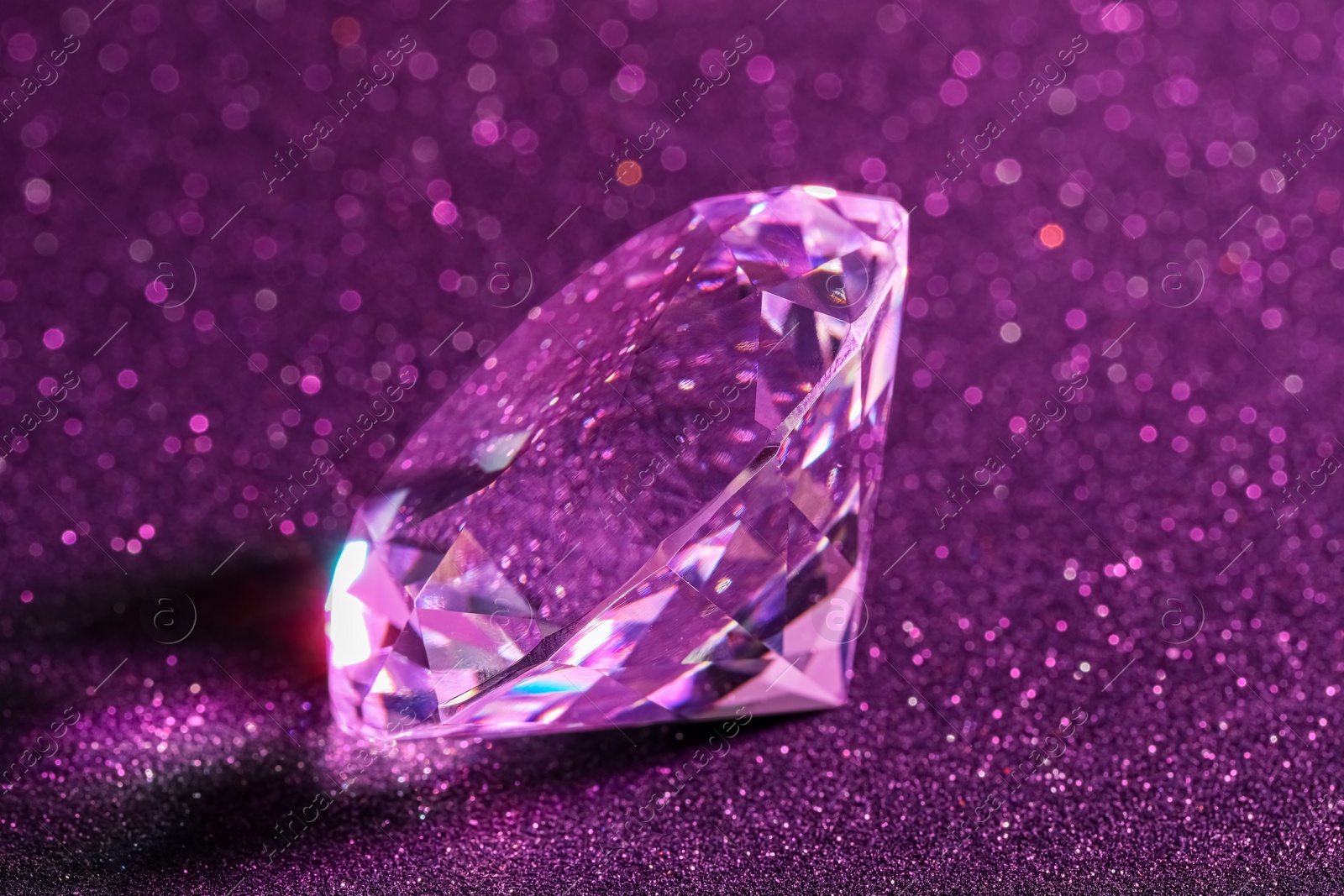 Photo of Beautiful shiny diamond on purple glitter background, closeup