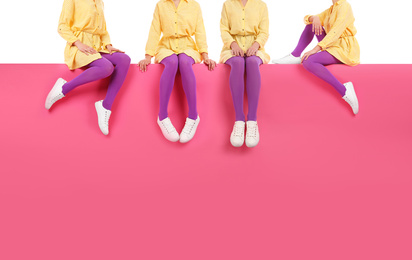 Women wearing violet tights and stylish shoes sitting on color background, closeup 