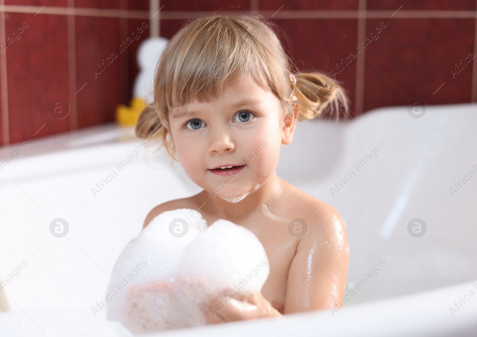 Photo of Little girl bathing in tub at home