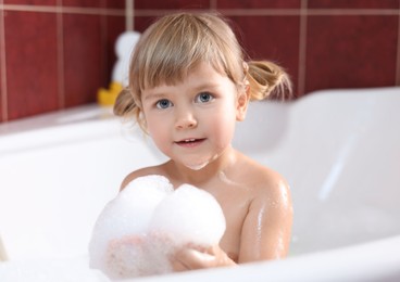 Little girl bathing in tub at home