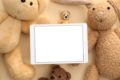 Photo of Modern tablet and stuffed animals on beige background, flat lay. Space for text