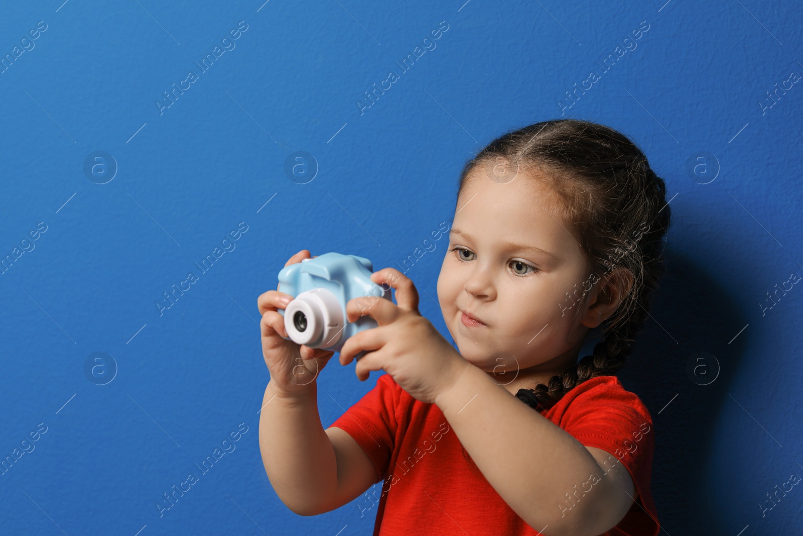 Photo of Little photographer taking picture with toy camera on blue background