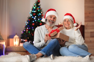 Happy couple opening Christmas gift at home