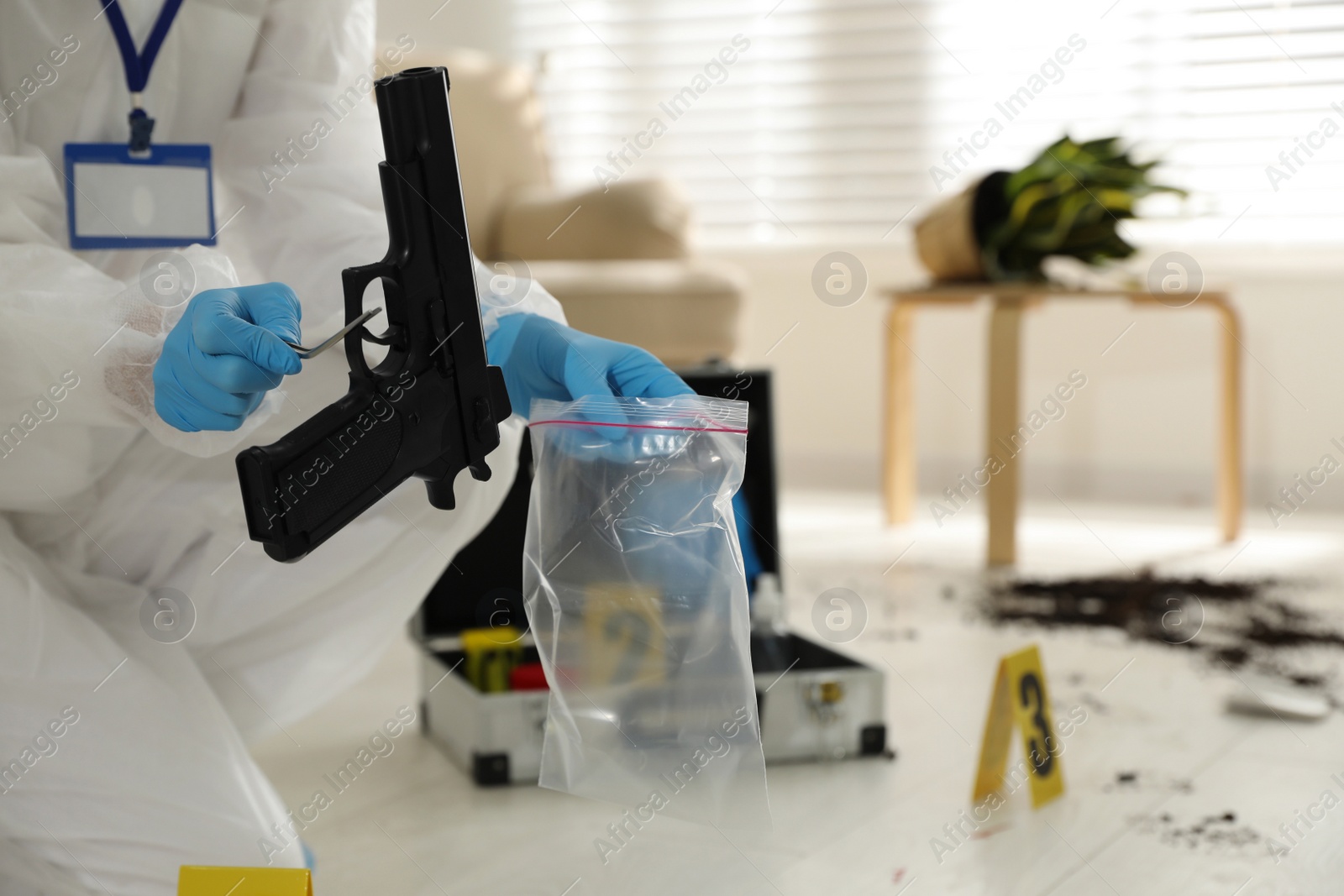 Photo of Investigator in protective suit working at crime scene indoors, closeup