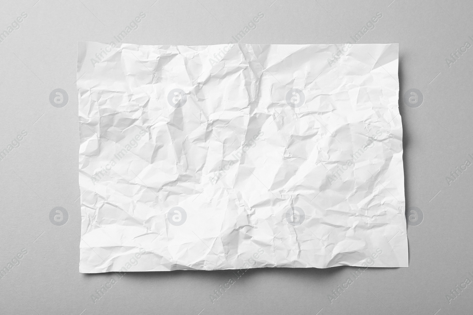 Photo of Sheet of white crumpled paper on grey background, top view