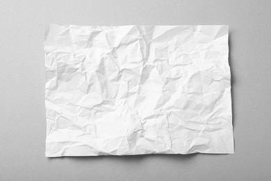 Photo of Sheet of white crumpled paper on grey background, top view