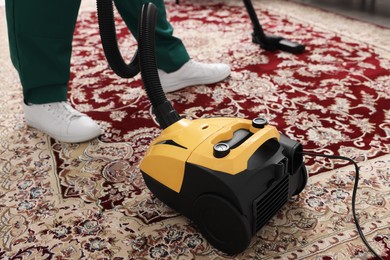 Photo of Dry cleaner's employee hoovering carpet with vacuum cleaner, closeup
