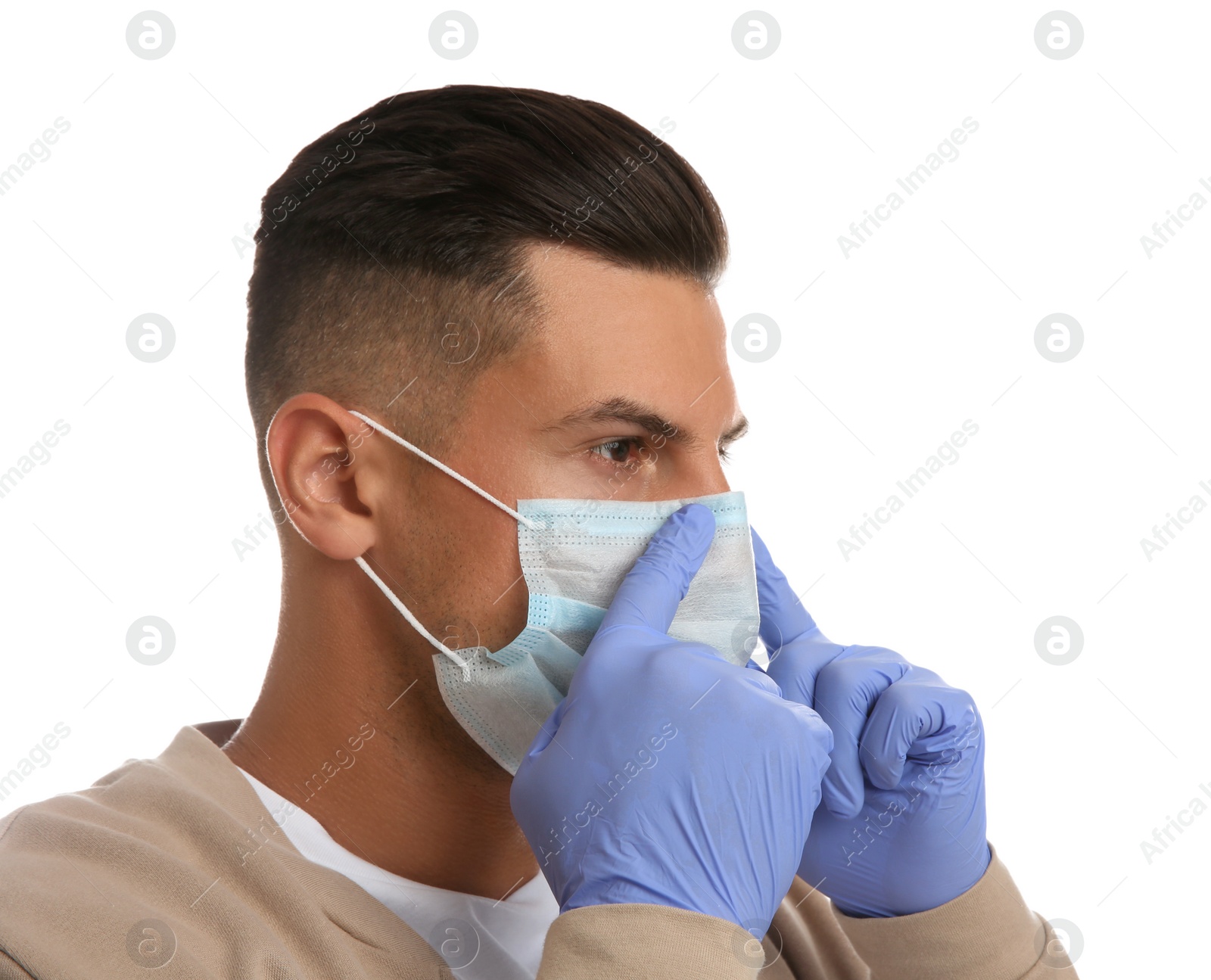 Photo of Man in medical gloves putting on protective face mask against white background