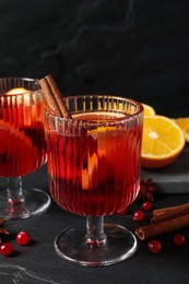 Photo of Aromatic punch drink and ingredients on black table