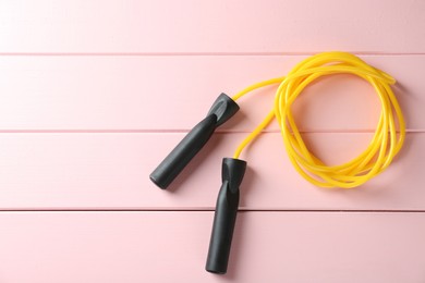 Skipping rope on pink wooden table, top view. Space for text