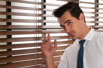 Photo of Handsome young man standing near window indoors