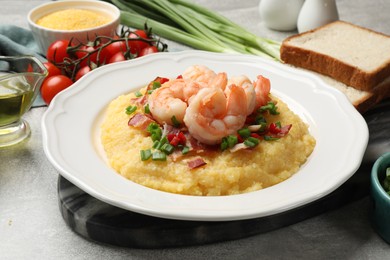 Plate with fresh tasty shrimps, bacon, grits, green onion and pepper on gray table, closeup