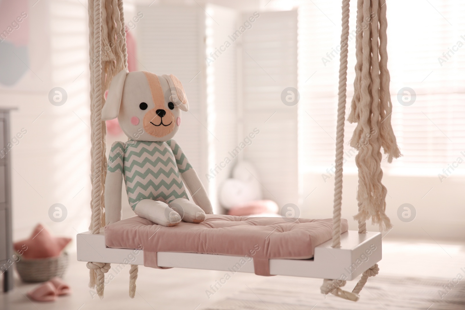 Photo of Beautiful swing with toy dog in room. Stylish interior design