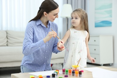 Photo of Mother and her little daughter painting with palms at home