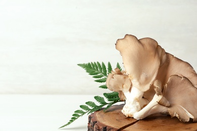 Wooden coaster with delicious organic oyster mushrooms on table, space for text