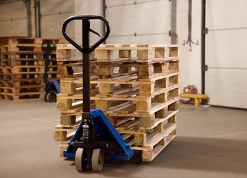 Modern manual forklift with wooden pallets in warehouse