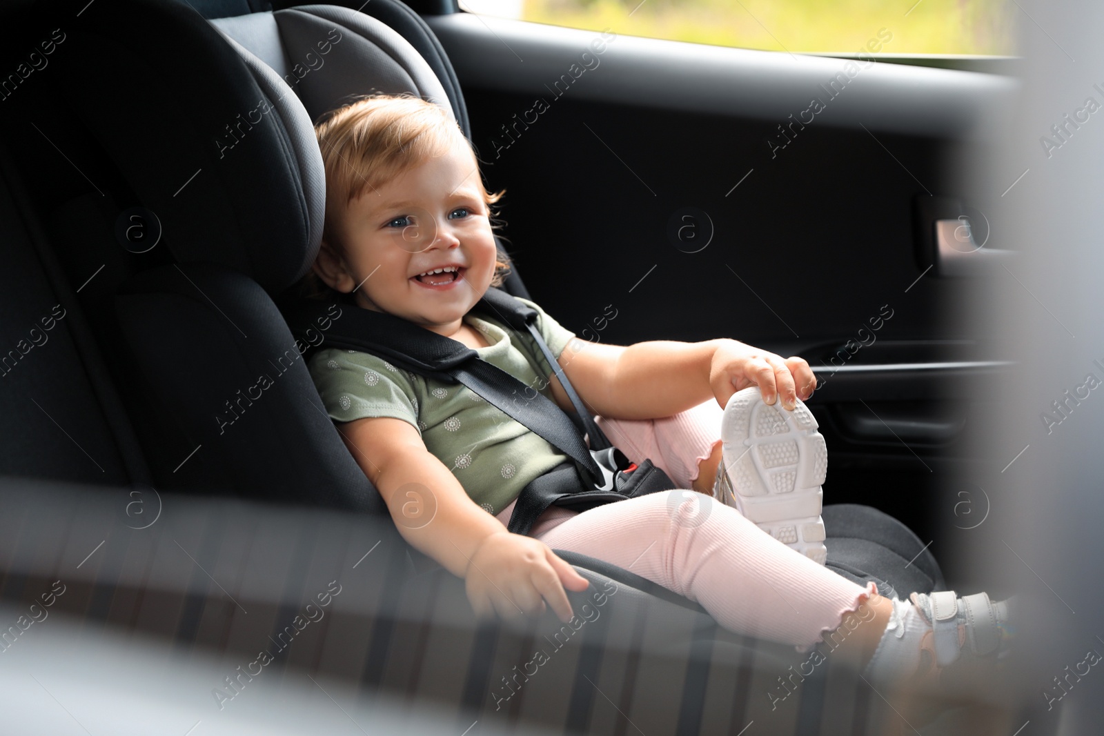 Photo of Cute little girl sitting in child safety seat inside car