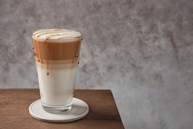 Photo of Glass of tasty caramel macchiato on table, Space for text