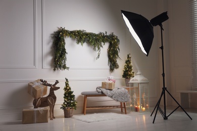 Photo of Beautiful Christmas themed photo zone with professional equipment and fir decor