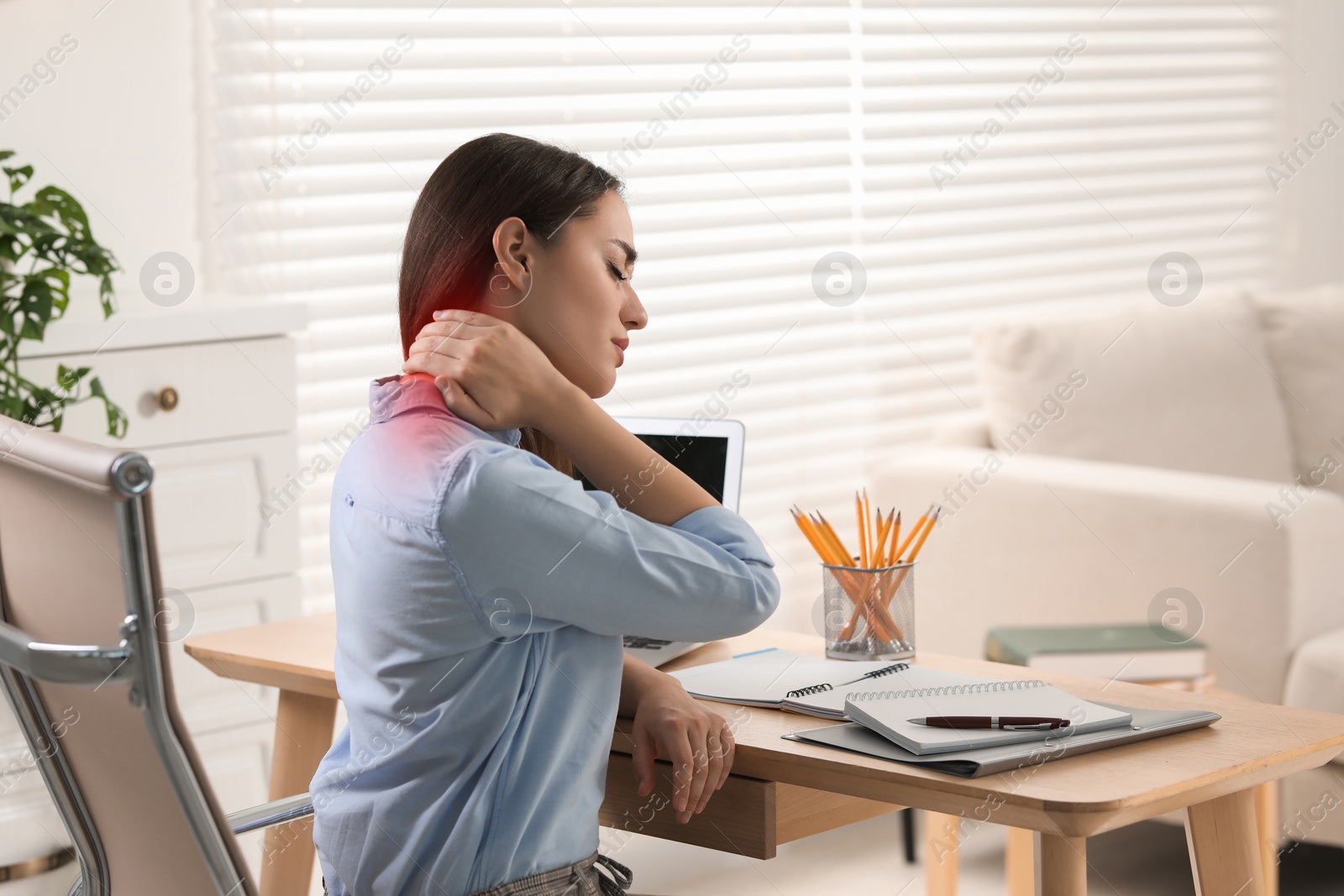 Image of Woman suffering from neck pain at table