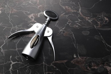 One wing corkscrew on black marble table. Space for text