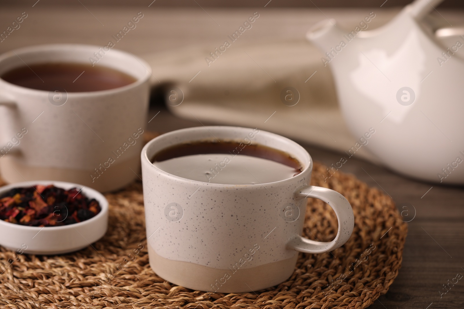 Photo of Aromatic tea and dry flower petals on wooden table, closeup