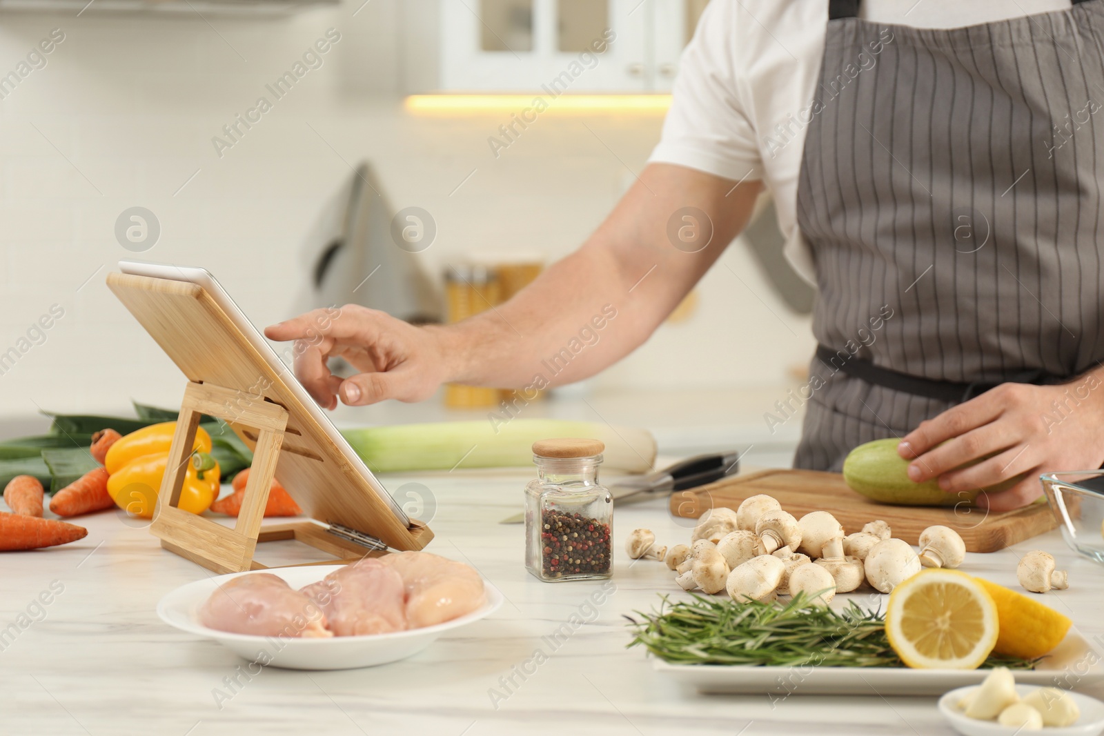 Photo of Man watching online cooking course via tablet in kitchen, closeup