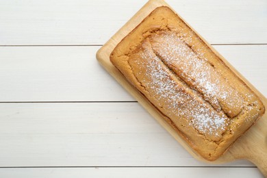 Delicious homemade yogurt cake with powdered sugar on white wooden table, top view. Space for text