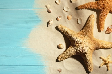 Photo of Flat lay composition with seashells, beach sand and space for text on wooden background