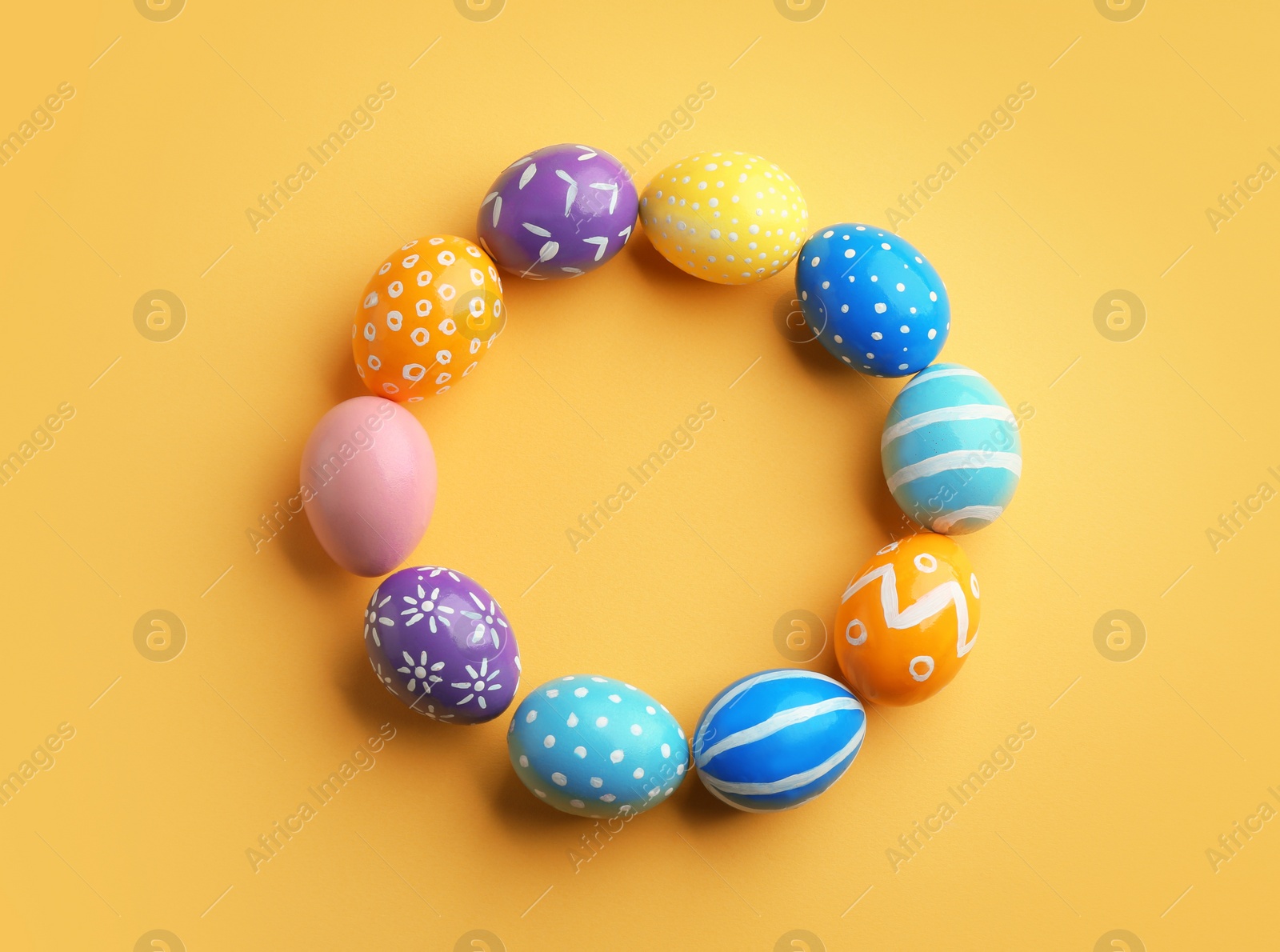 Photo of Frame made of painted Easter eggs on color background, top view. Space for text