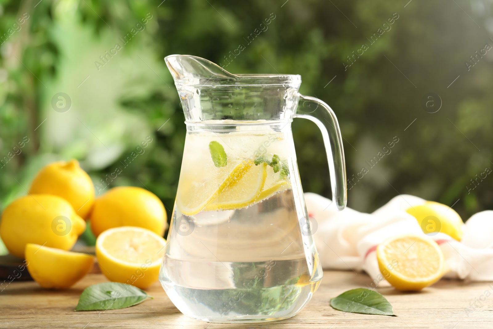 Photo of Glass jug of cold lemonade on wooden table