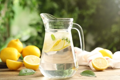 Photo of Glass jug of cold lemonade on wooden table