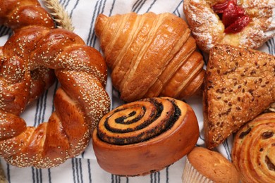 Different tasty freshly baked pastries on striped tablecloth, flat lay