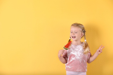Photo of Cute little girl with candy on color background. Space for text