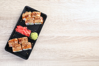 Tasty sushi rolls in box on wooden table, top view with space for text. Food delivery