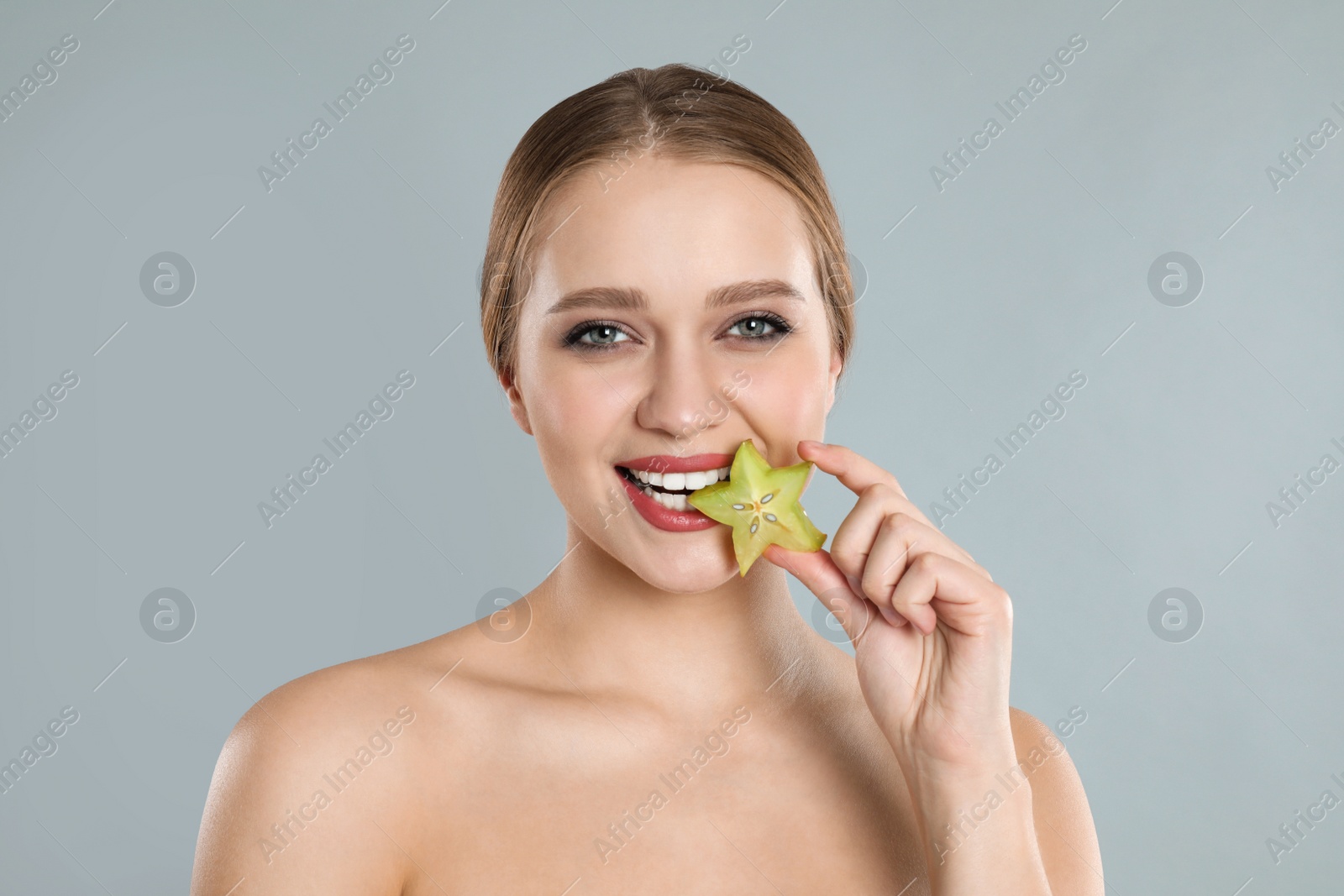 Photo of Young woman with slice of carambola on grey background. Vitamin rich food