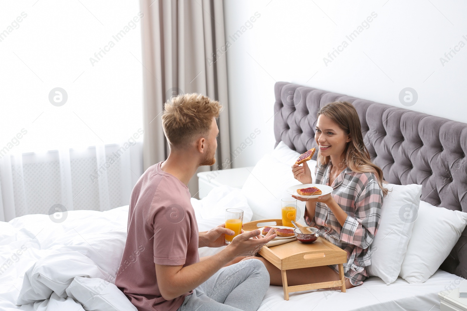 Photo of Happy young couple having romantic breakfast on bed at home