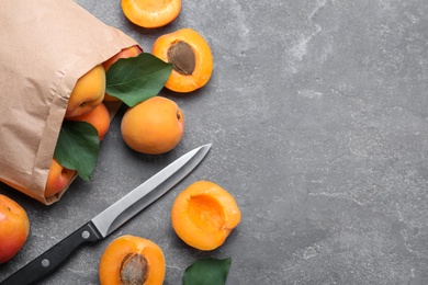 Photo of Many fresh ripe apricots and knife on grey table, flat lay. Space for text