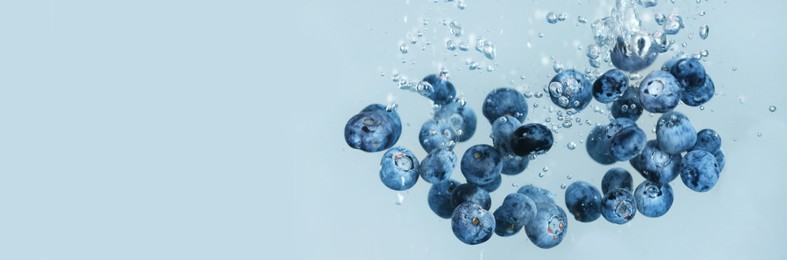 Image of Fresh ripe blueberries falling in water on grey background, space for text. Banner design