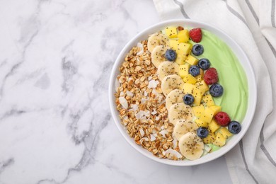 Photo of Tasty matcha smoothie bowl served with fresh fruits and oatmeal on white marble table, top view with space for text. Healthy breakfast