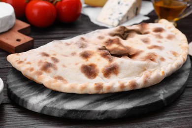 Photo of One delicious cheese calzone on wooden table, closeup