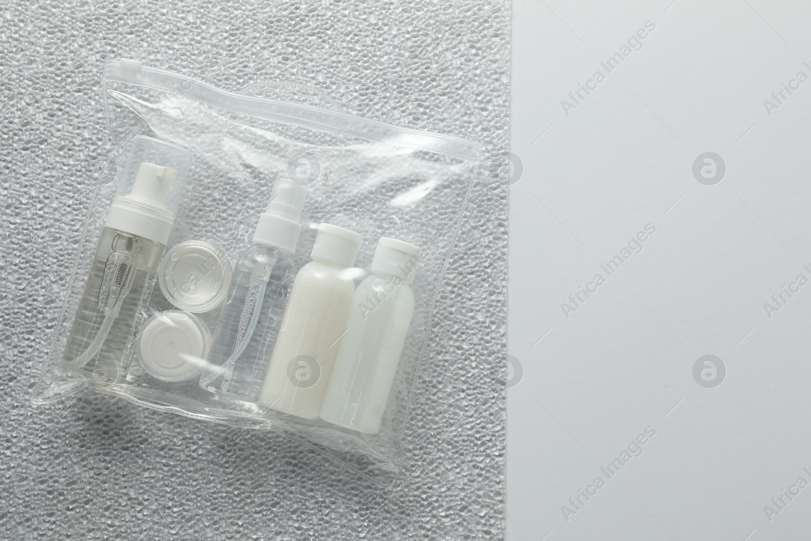 Photo of Cosmetic travel kit in plastic bag on color background, top view and space for text. Bath accessories