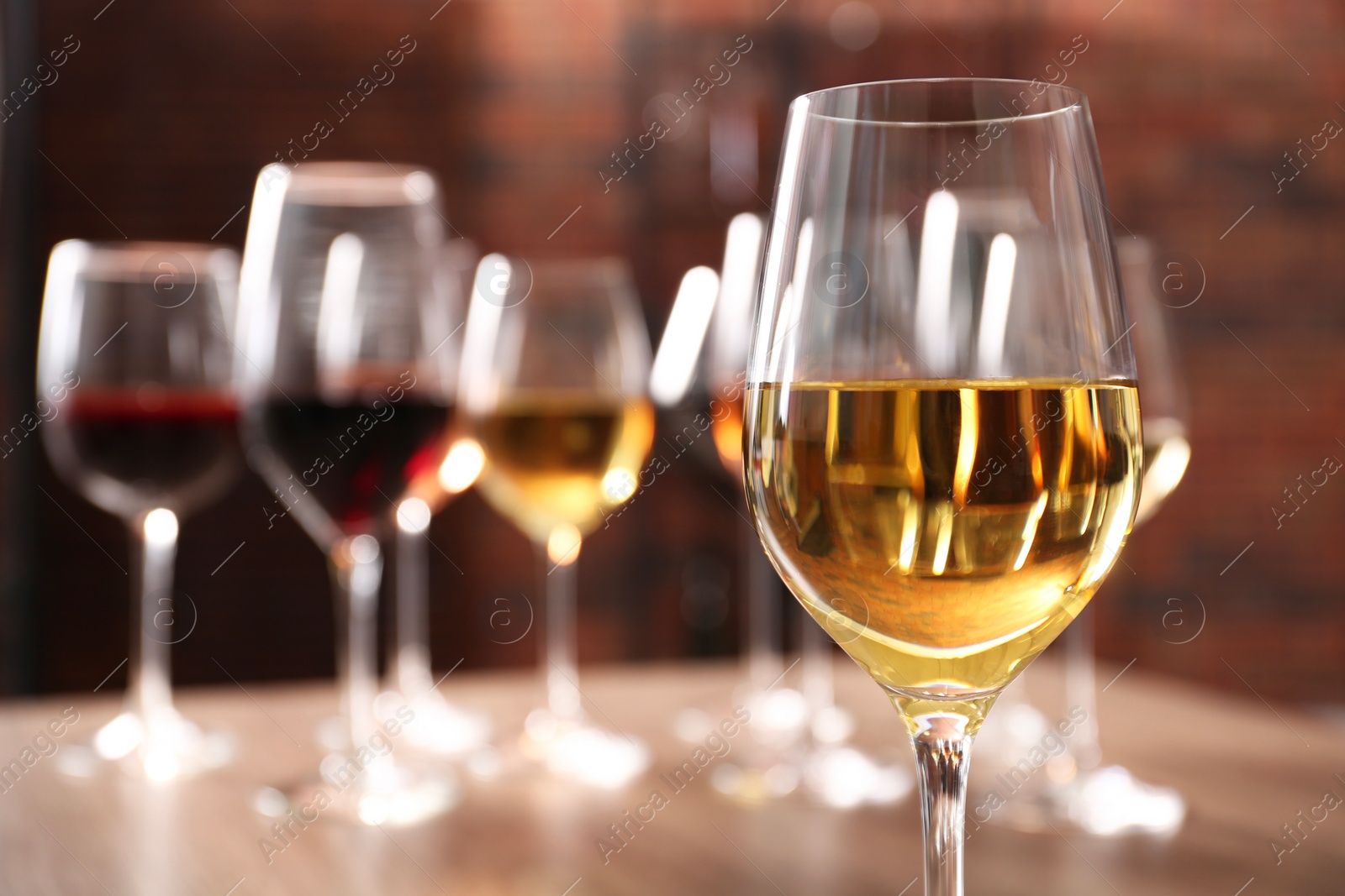 Photo of Tasty white wine in glass against blurred background, space for text